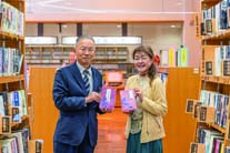 藤井栄治図書館長に冊子を手渡す坂梨千秋さん